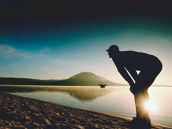 Homme faisant de l'exercice sur la plage. Silhouette de l'homme actif faisant de l'exercice et s'étirant au lac — Photo