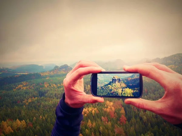 Chytrý telefon mobilní fotografie zamlžené krajiny. Zaměřit se na detail s telefonem v ruce člověka. — Stock fotografie