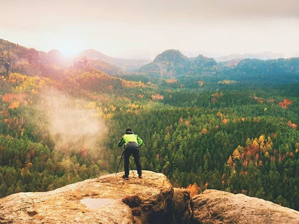 Photographer takes picture of spring nature from sharp rocks. Hiker in green jacket stay with camera on tripod — Stock Photo, Image