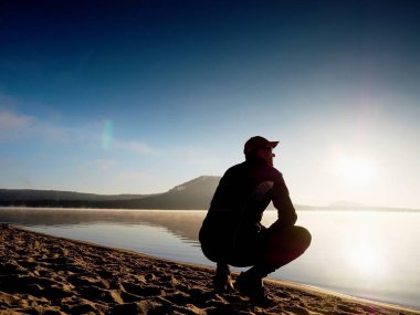 Kumsalda egzersiz adam. Egzersiz ve gölde germe etkin adam silüeti