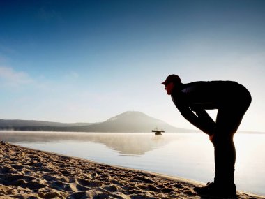 Kumsalda egzersiz adam. Egzersiz ve gölde germe etkin adam silüeti