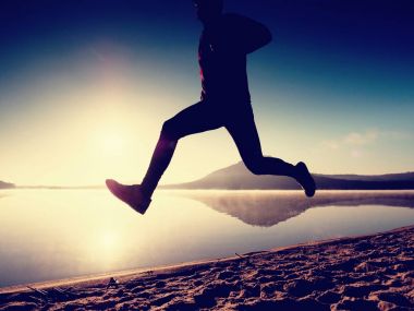 Kumsalda egzersiz adam. Egzersiz ve gölde germe etkin adam silüeti