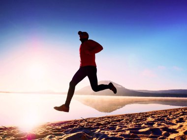 Kumsalda egzersiz adam. Egzersiz ve gölde germe etkin adam silüeti