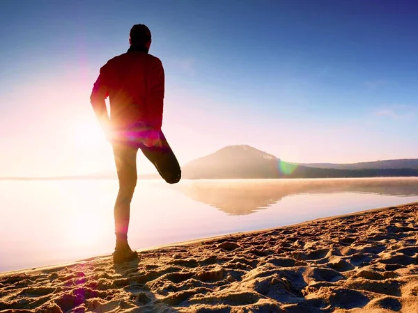 해변에서 운동 하는 남자. 운동 하 고 스트레칭 호수에 적극적인 남자의 실루엣 — 스톡 사진
