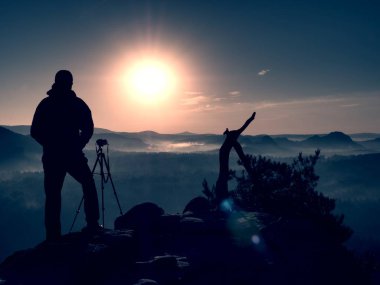 Amatör fotoğrafçı kaya tepe üzerinde ayna kamera ile fotoğraf çeker. Rüya gibi adamlara manzara, Bahar Turuncu pembe puslu sunrise bir güzel vadi