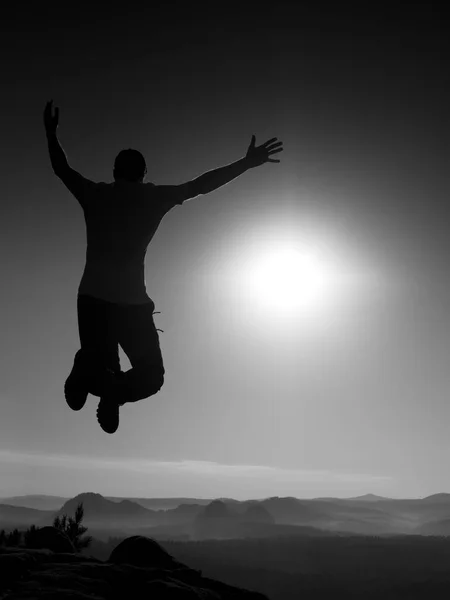 Young crazy man is jumping on rock. Silhouette of jumping man — Stock Photo, Image