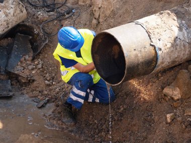 İşçi El değirmeni ile metal tüp kesti. Aşağı ıslak kil kıvılcımlar uçuşuyordu. Personel Emanet pıhtı içinde çalışma