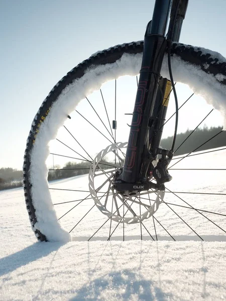 La rueda delantera de la bicicleta de montaña jab en nieve en polvo. Camino perdido bajo profunda deriva de nieve . — Foto de Stock