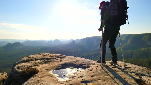 Turist med medicin krycka ovanför huvud uppnåtts bergstopp. Hiker med brutet ben i stöldskyddet. Djupt misty valley bellow silhuetten av lycklig man med handen i luften. Våren morgonen — Stockvideo