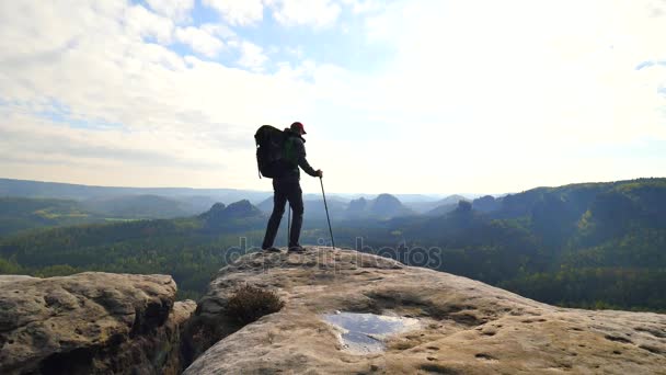 Tall tourist guide looking in paper  map. Hiker is  hiking with trekking poles and heavy backpack.  Man hiker on the rocky edge check the position in the map.  Wild hilly nature park. — Stock Video