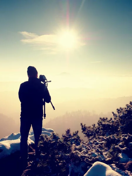 L'homme prend des photos avec un appareil photo sur un rocher pointu. Paysage brouillard rêveur — Photo