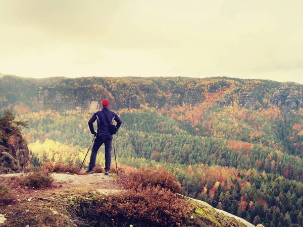 Tourist guide in black. Hiker with sportswear stand on view point above fall colors valley.