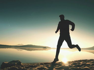 Gündoğumu kıyıda çalışan etkin atlet runner silüeti. Sabah sağlıklı yaşam tarzı egzersiz