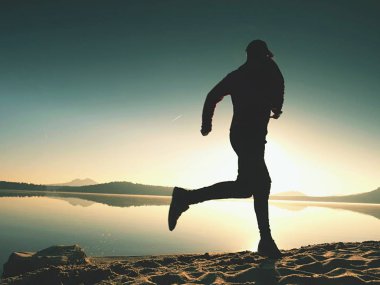 Gündoğumu kıyıda çalışan etkin atlet runner silüeti. Sabah sağlıklı yaşam tarzı egzersiz