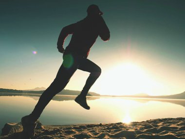 Gündoğumu kıyıda çalışan etkin atlet runner silüeti. Sabah sağlıklı yaşam tarzı egzersiz
