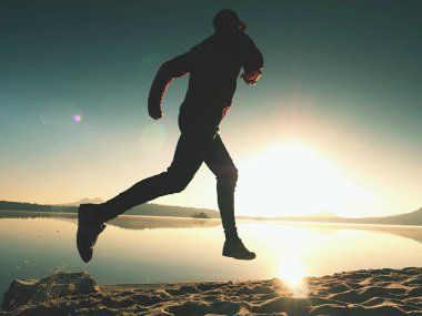 Gündoğumu kıyıda çalışan etkin atlet runner silüeti. Sabah sağlıklı yaşam tarzı egzersiz