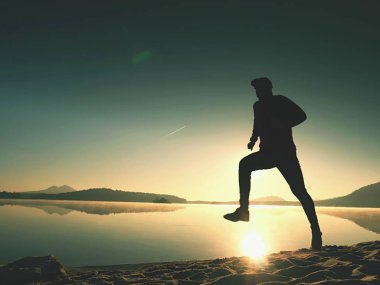 Gündoğumu kıyıda çalışan etkin atlet runner silüeti. Sabah sağlıklı yaşam tarzı egzersiz