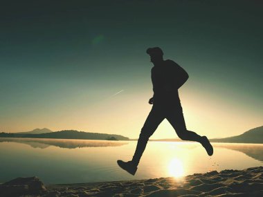 Gündoğumu kıyıda çalışan etkin atlet runner silüeti. Sabah sağlıklı yaşam tarzı egzersiz