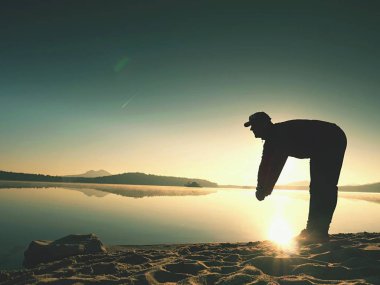 Derin nefes alma runner siluet elleriyle diz çöküyorum. Kas germe adama yan görünüm 