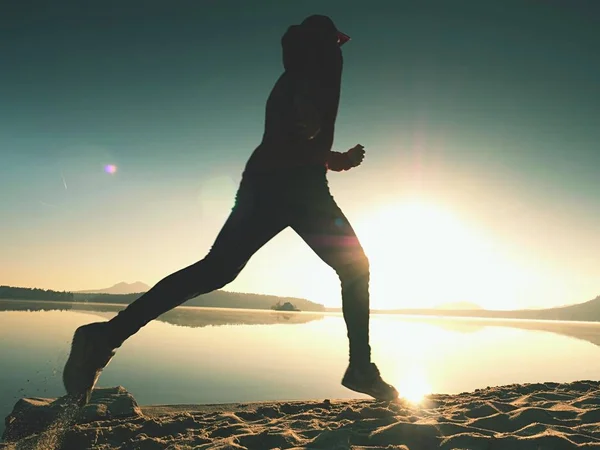 Silhueta de atleta ativo corredor correndo na costa do nascer do sol. Manhã exercício de estilo de vida saudável — Fotografia de Stock