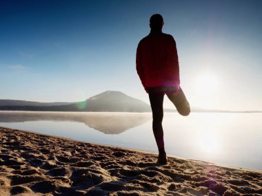 Kumsalda egzersiz adam. Egzersiz ve gölde germe etkin adam silüeti