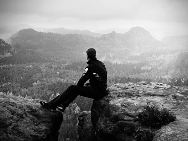 Man in black sit on cracked rocky empires. Melancholy misty day — Stock Photo, Image