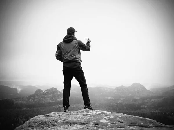 El hombre toma fotos con el teléfono inteligente en el pico del imperio del rock. Niebla melancólica — Foto de Stock