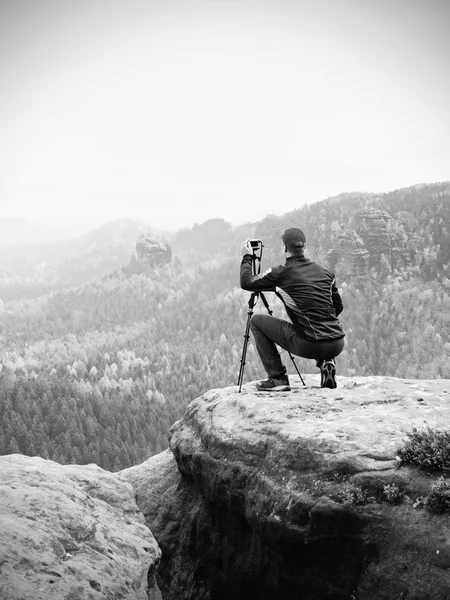 Fotógrafo al aire libre con trípode y cámara en rock thinking. Valle otoñal —  Fotos de Stock