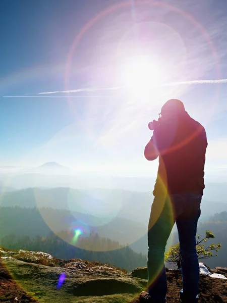 Homem alto está tirando foto por câmera de espelho no pescoço. Pico rochoso nevado da montanha . — Fotografia de Stock