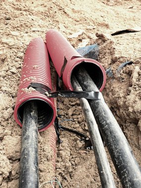 Koruyucu Hdpe boru içinde siyah kablolar ile hendek kazı. Metalik ve fiber optik kablo hatları.