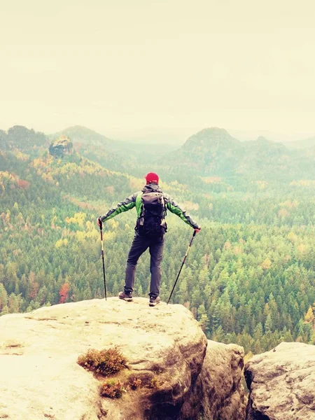 Guide touristique sur le sommet avec poteaux à la main et sac à dos lourd. Randonneur vert jakcet nad rouge cap — Photo