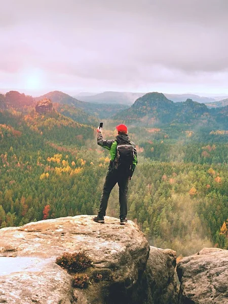 Touristin mit Rucksack bleibt auf Klippe und macht Fotos mit Smartphone vom Regental. — Stockfoto