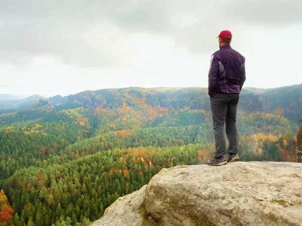 Wanderer am Felsenende über dem Tal. Mann wacht über nebeliges und herbstliches Morgental zur strahlenden Morgensonne. — Stockfoto