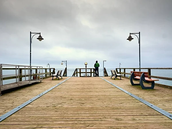 Mann in Grün auf einem Maulwurf am Geländer. Herbstnebel, Regentag. — Stockfoto