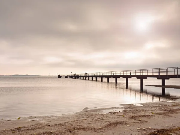 Drewniany most nad morzem o zachodzie słońca. Pogoda bezwietrzny, spokojny cichy dzień w zatoce. — Zdjęcie stockowe