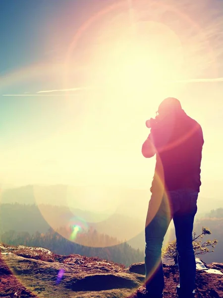 Homem alto está tirando foto por câmera de espelho no pescoço. Pico rochoso nevado da montanha . — Fotografia de Stock