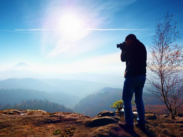 Grand homme prend des photos par caméra miroir sur le cou. Pic rocheux enneigé de montagne . — Photo
