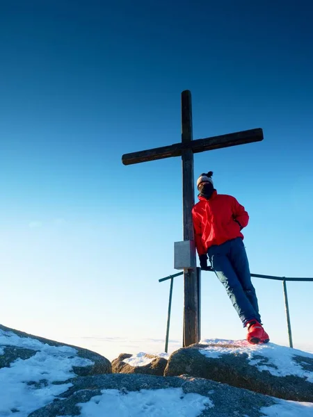 Tourist in winter clothes on summit  with crucifix — Stock Photo, Image