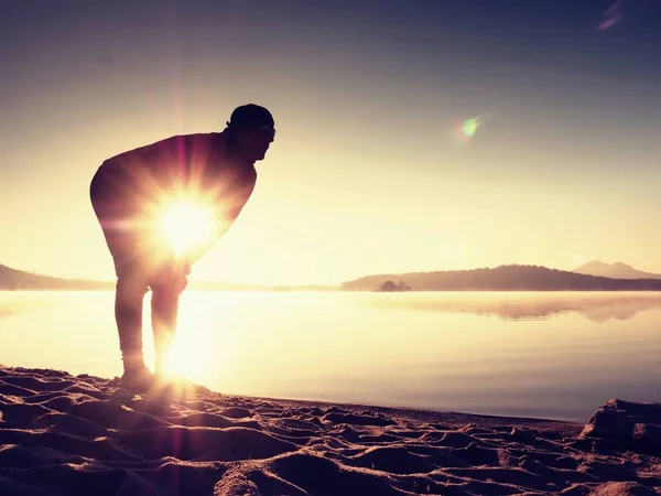 Diepe ademhaling runner silhouet gebogen met handen op knieën. Zijaanzicht naar man spieren uit te rekken — Stockfoto