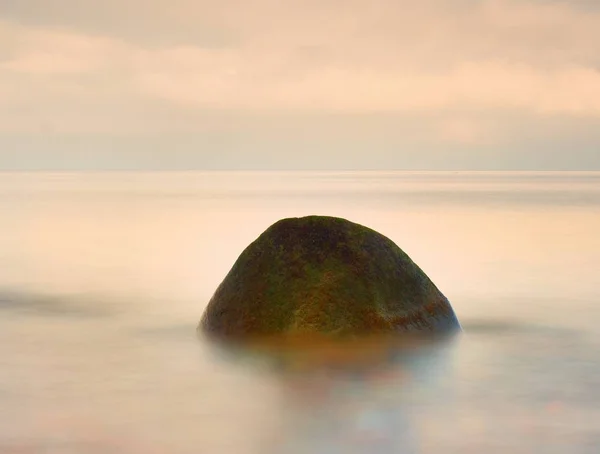 Piedra solitaria en mar liso. Hermoso paisaje marino con poca luz. Mar y roca al atardecer . — Foto de Stock