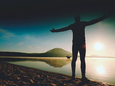 Kumsalda egzersiz adam. Egzersiz ve gölde germe etkin adam silüeti