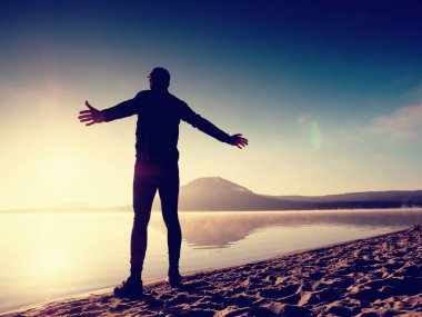 Kumsalda egzersiz adam. Egzersiz ve gölde germe etkin adam silüeti