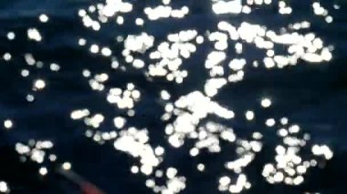 Su küçük dalgalar geçen, su üstüne renkli gölgeler sparkles ve ışık yansımaları ile hareket 