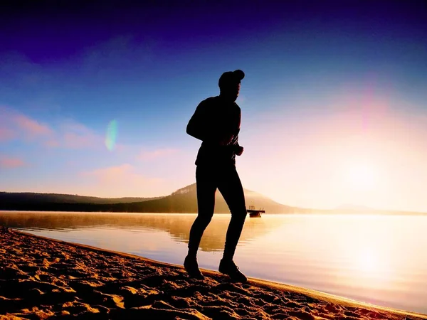 Tall zmieścić człowiek biegnie wzdłuż brzegu morza w rano. Zdrowy mężczyzna jogging na plaży. — Zdjęcie stockowe