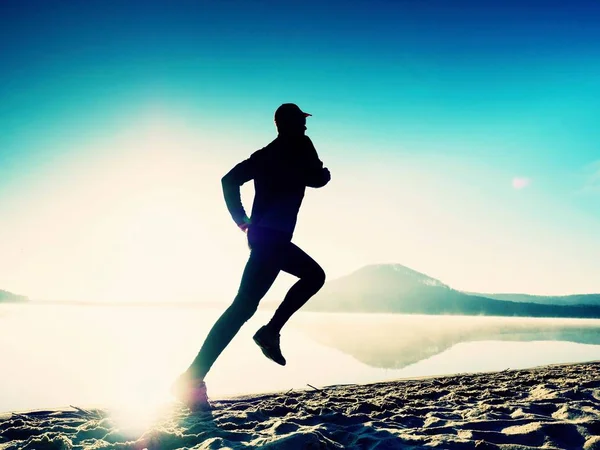 Vysoká vešel muž běží podél břehu moře ráno. Zdravý muž běhání na pláži. — Stock fotografie