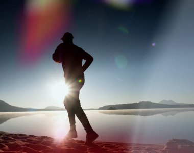 Plajda çalışan adam. Kumlu bir plaj üzerinde gündoğumu sırasında adam koşu beyzbol şapkası çalıştırmak sporcu. Gün batımında sahilde atlama adam