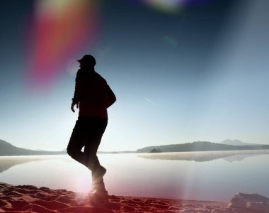 Plajda çalışan adam. Kumlu bir plaj üzerinde gündoğumu sırasında adam koşu beyzbol şapkası çalıştırmak sporcu. Gün batımında sahilde atlama adam