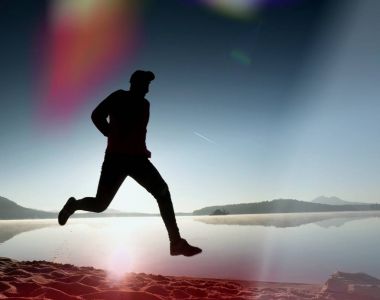 Gündoğumu kıyıda çalışan etkin atlet runner silüeti. Sabah sağlıklı yaşam tarzı egzersiz