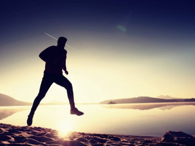 Gündoğumu kıyıda çalışan etkin atlet runner silüeti. Sabah sağlıklı yaşam tarzı egzersiz