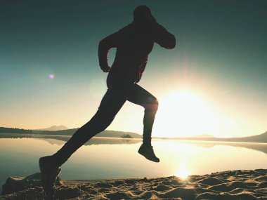 Gündoğumu kıyıda çalışan etkin atlet runner silüeti. Sabah sağlıklı yaşam tarzı egzersiz